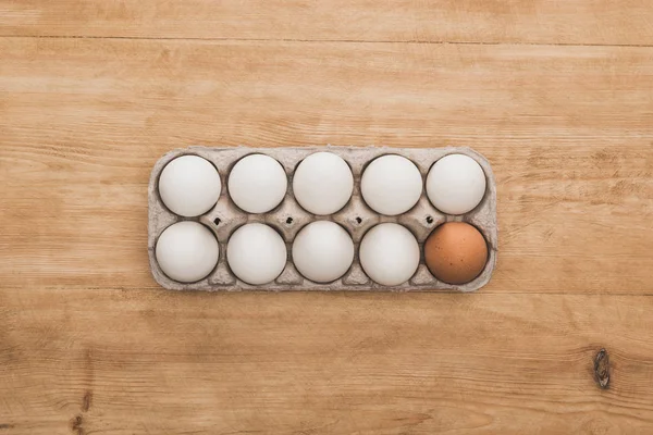 Вид куриных яиц в картонной коробке на деревянном столе — стоковое фото