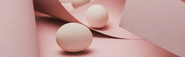 Fuoco selettivo di uova di pollo in vortici rosa carta a spirale, colpo panoramico — Foto stock