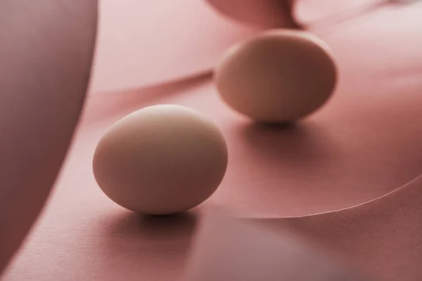 Enfoque selectivo de huevos de pollo en sombra en espirales de papel rosa remolinos - foto de stock