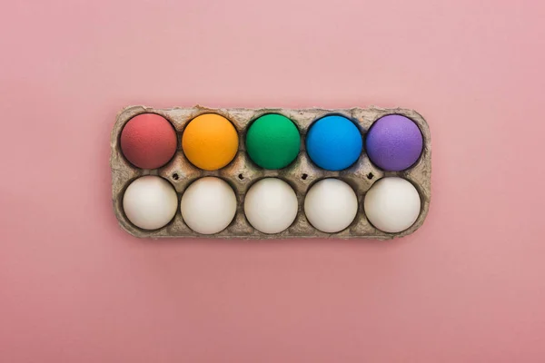 Vista superior de ovos de Páscoa pintados em caixa de papelão sobre fundo rosa — Fotografia de Stock