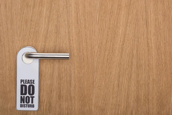 Wooden hotel room door with please do no disturb sign on handle — Stock Photo