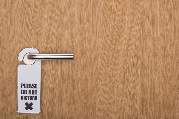 Wooden hotel room door with please do no disturb sign on handle — Stock Photo