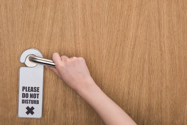 Cropped view of woman holding door handle with please do no disturb sign — Stock Photo