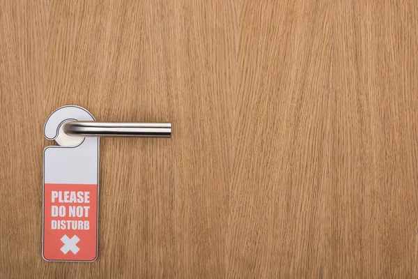 Wooden hotel room door with please do no disturb sign on handle — Stock Photo