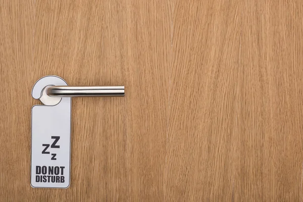 Wooden hotel room door with do no disturb sign on handle — Stock Photo