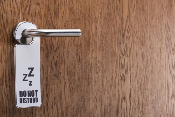 Wooden hotel room door with do no disturb sign on handle — Stock Photo