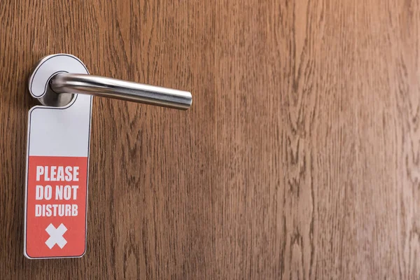 Puerta de la habitación del hotel de madera con por favor no molestar signo en la manija - foto de stock