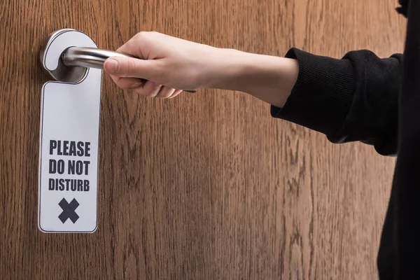 Vue partielle de la femme tenant poignée de porte avec s'il vous plaît ne pas déranger signe — Photo de stock