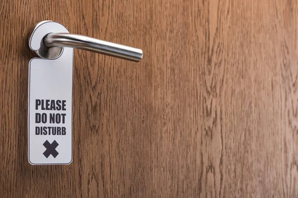 Wooden hotel room door with please do no disturb sign on handle — Stock Photo