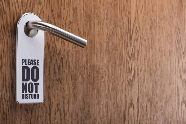 Wooden hotel room door with please do no disturb sign on handle — Stock Photo