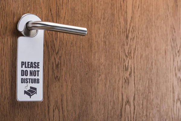 Wooden hotel room door with please do no disturb sign on handle — Stock Photo