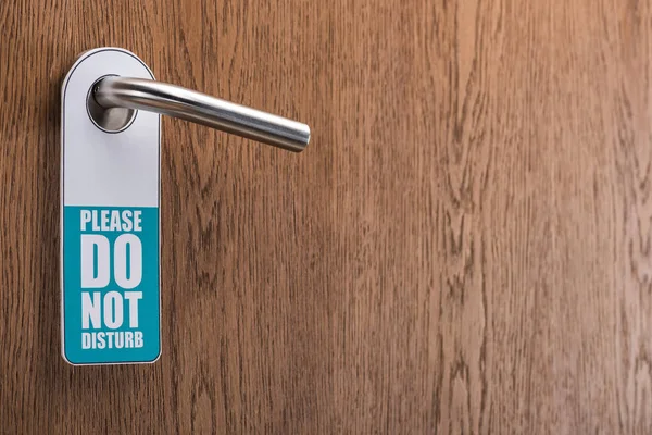 Wooden hotel room door with please do no disturb sign on handle — Stock Photo