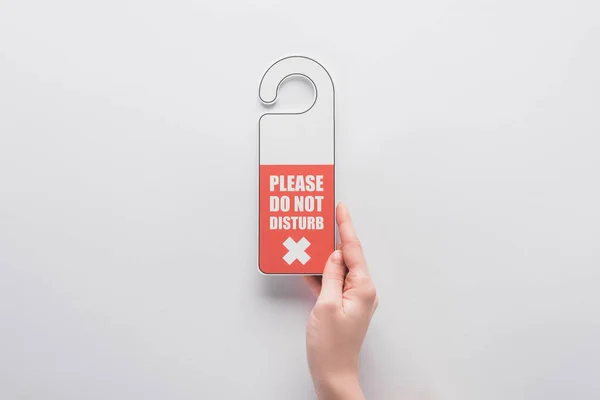 Cropped view of woman holding please do no disturb sign on white background — Stock Photo