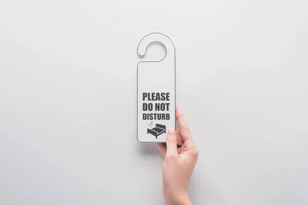 Cropped view of woman holding please do no disturb sign on white background — Stock Photo