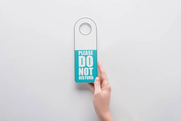 Cropped view of woman holding please do no disturb sign on white background — Stock Photo