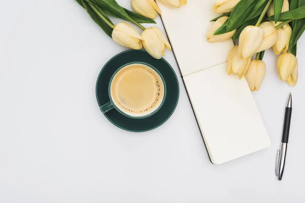 Draufsicht auf Tulpen, leeres Notizbuch mit Stift und frischem Kaffee isoliert auf Weiß — Stockfoto