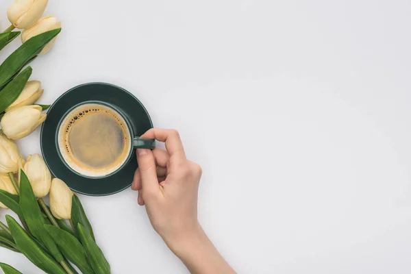 Vista ritagliata di donna in possesso di tazza di caffè fresco vicino a tulipani isolati su bianco — Foto stock