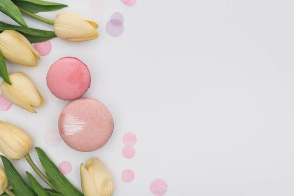 Vue de dessus des tulipes, macarons roses et confettis violets isolés sur blanc — Photo de stock