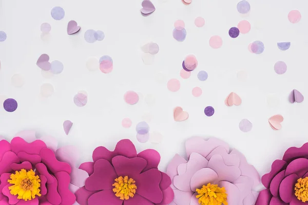 Vista dall'alto di fiori rosa e viola tagliati su carta vicino a coriandoli isolati su bianco — Foto stock