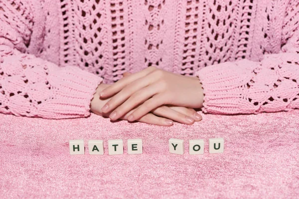 Cropped view of woman in sweater near hate you lettering on pink velour cloth, girlish concept — Stock Photo