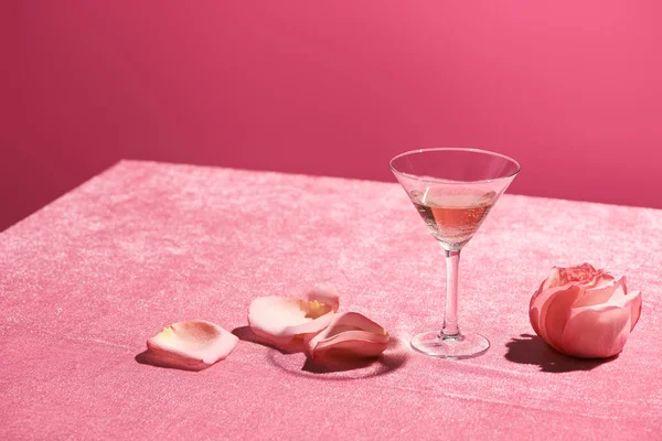 Rosenwein im Glas in der Nähe von Blütenblättern und Rosenknospe auf samtrosa Tuch isoliert auf rosa, mädchenhaftes Konzept — Stockfoto