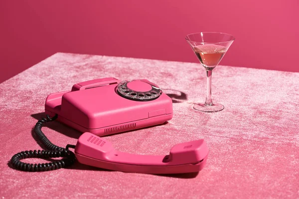 Vin rose en verre près de téléphone vintage sur tissu velours rose isolé sur rose, concept girlish — Photo de stock