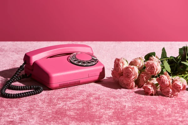 Rosas y teléfono vintage en tela de terciopelo rosa aislado en rosa, concepto femenino — Stock Photo