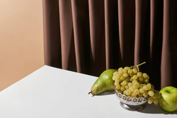 Classic still life with fruits on table near curtain isolated on beige — Stock Photo