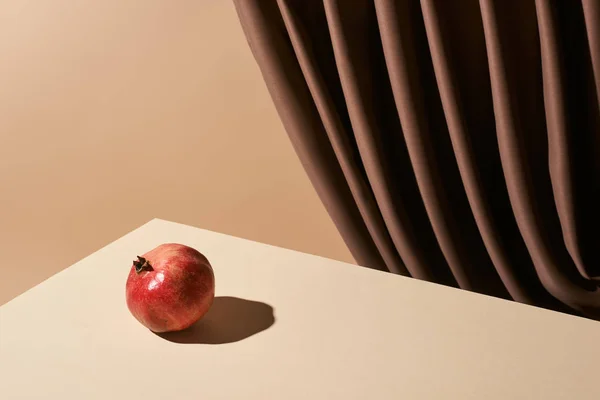 Classic still life with pomegranate on table near curtain isolated on beige — Stock Photo