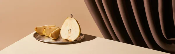Classic still life with pear on silver plate on table near curtain isolated on beige, panoramic shot — Stock Photo