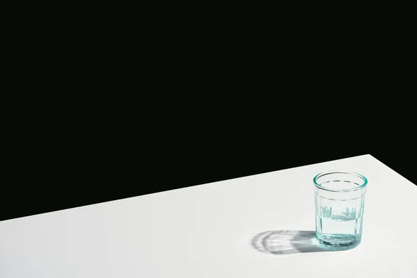 Classic still life with water in glass on white table isolated on black — Stock Photo