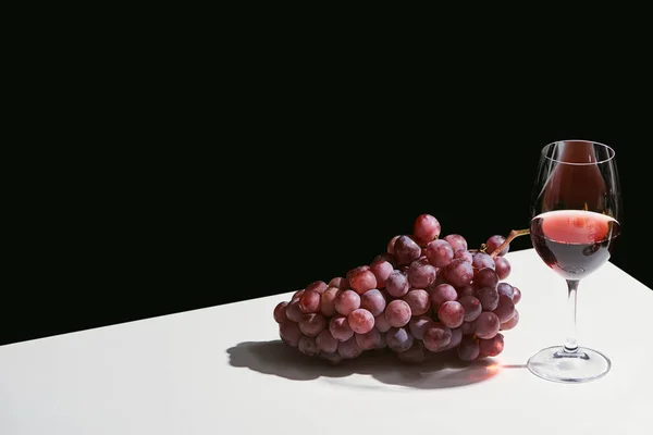 Klassisches Stillleben mit Trauben und Rotwein auf weißem Tisch isoliert auf schwarzem Tisch — Stockfoto