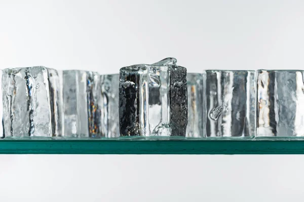 Селективное фокусирование прозрачных прозрачных квадратных кубиков льда в линии, изолированных на белом — стоковое фото