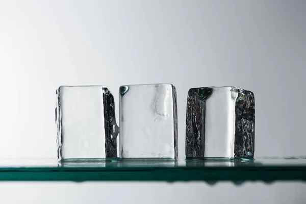 Messa a fuoco selettiva di fusione trasparente cubetti di ghiaccio quadrati trasparenti isolati su bianco — Foto stock