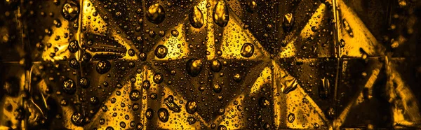 Vista ravvicinata del vetro sfaccettato geometrico con illuminazione gialla nel buio, scatto panoramico — Foto stock