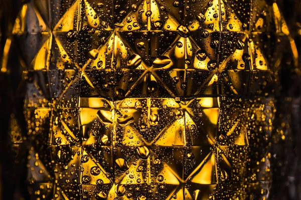 Vue rapprochée du verre géométrique à facettes avec éclairage jaune dans l'obscurité — Photo de stock