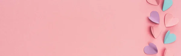 Vista dall'alto di cuori di carta colorati su sfondo rosa, colpo panoramico — Foto stock