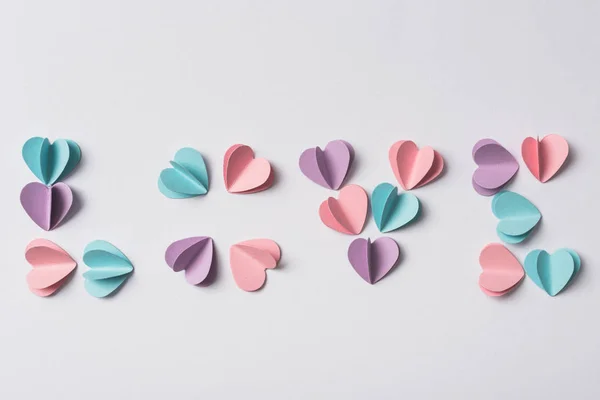 Vue du dessus de lettrage d'amour fait de coeurs en papier coloré sur fond blanc — Photo de stock