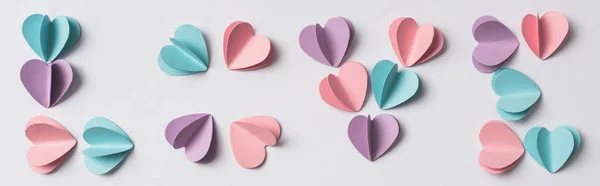 Vue du dessus du lettrage d'amour fait de coeurs en papier coloré sur fond blanc, vue panoramique — Photo de stock