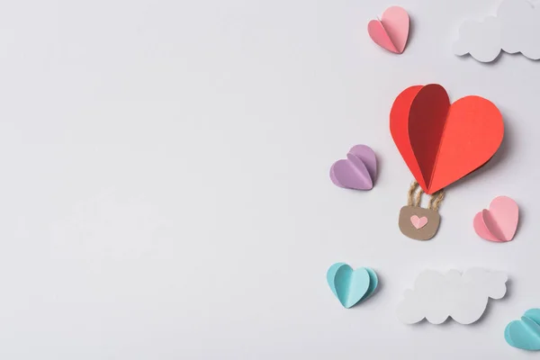 Top view of colorful paper hearts and air balloon with clouds on white background — Stock Photo