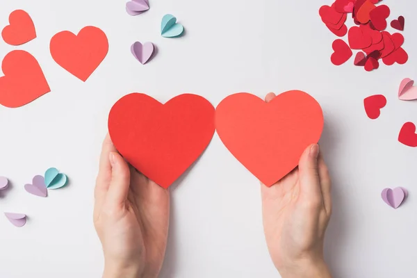 Vista parcial de la mujer sosteniendo corazones en forma de corazón rojo en blanco sobre fondo blanco - foto de stock