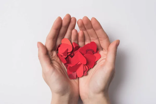 Partial view of woman holding paper red hearts on white background — Stock Photo