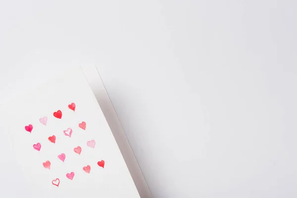 Vista superior de la tarjeta de felicitación de San Valentín con corazones rojos sobre fondo blanco - foto de stock