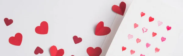 Vista superior de la tarjeta de felicitación de San Valentín y corazones rojos de papel sobre fondo blanco, plano panorámico - foto de stock