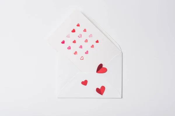 Vue du haut de la carte de vœux de Saint-Valentin dans une enveloppe avec des cœurs rouges sur fond blanc — Photo de stock