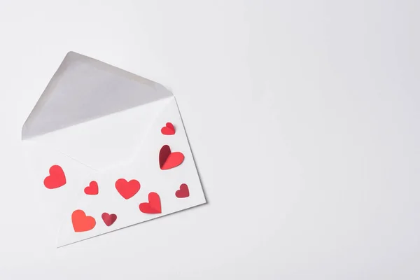 Vista superior del sobre de San Valentín con corazones rojos sobre fondo blanco - foto de stock