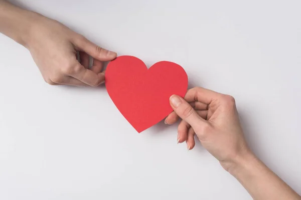 Vista recortada de las mujeres sosteniendo el corazón rojo sobre fondo blanco — Stock Photo