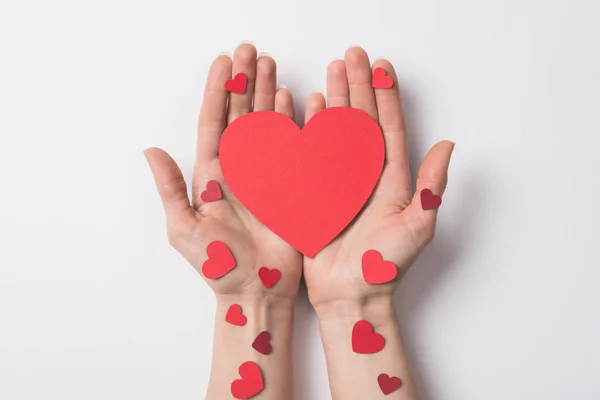 Cropped view of woman holding red hearts on white background — Stock Photo