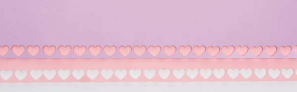 Top view of pink, violet paper with cut out hearts on white background, panoramic shot — Stock Photo