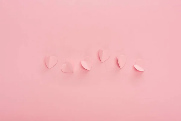 Vista superior de corazones de papel rosa sobre fondo rosa - foto de stock